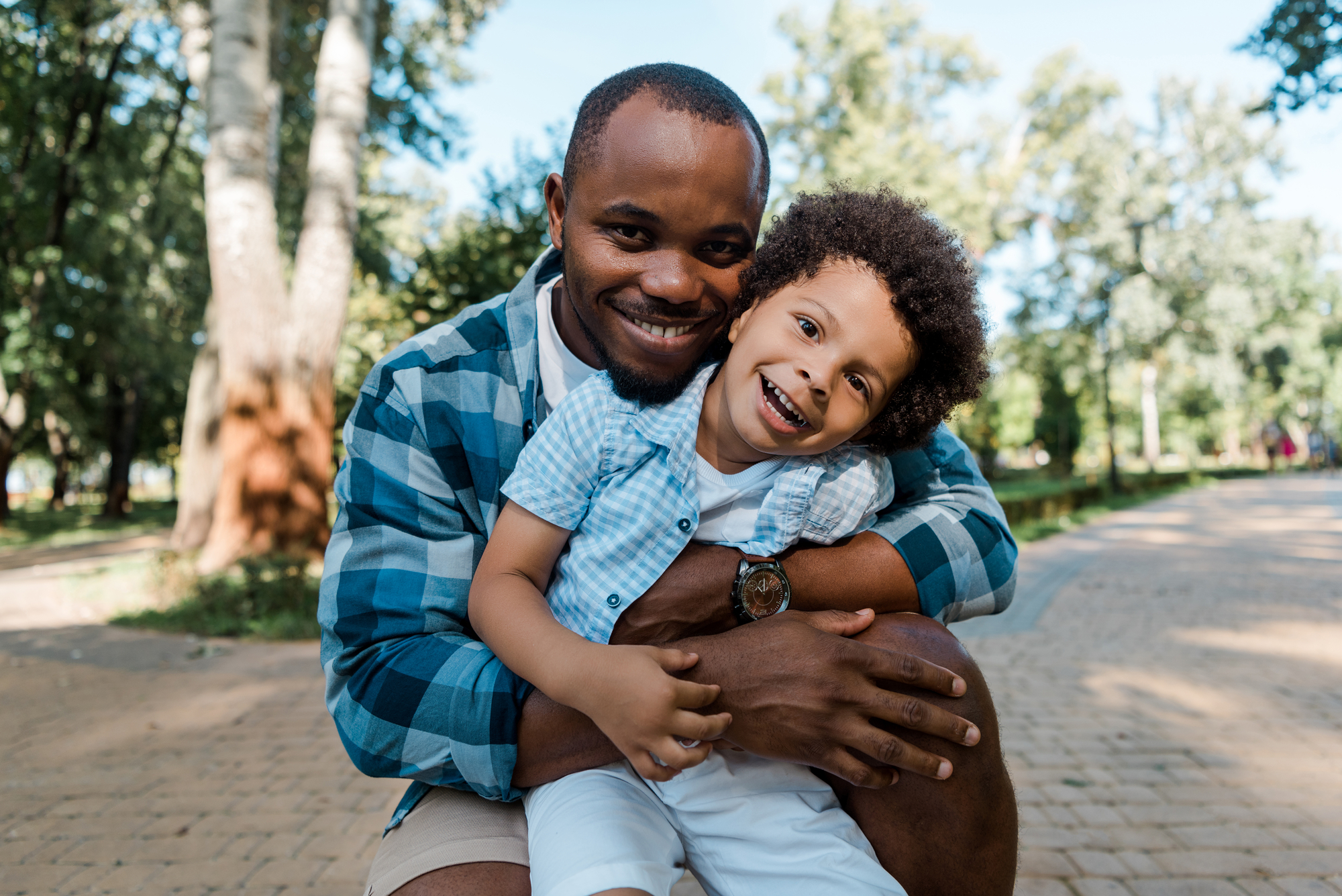 Cheerful african american man hugging cute curly son