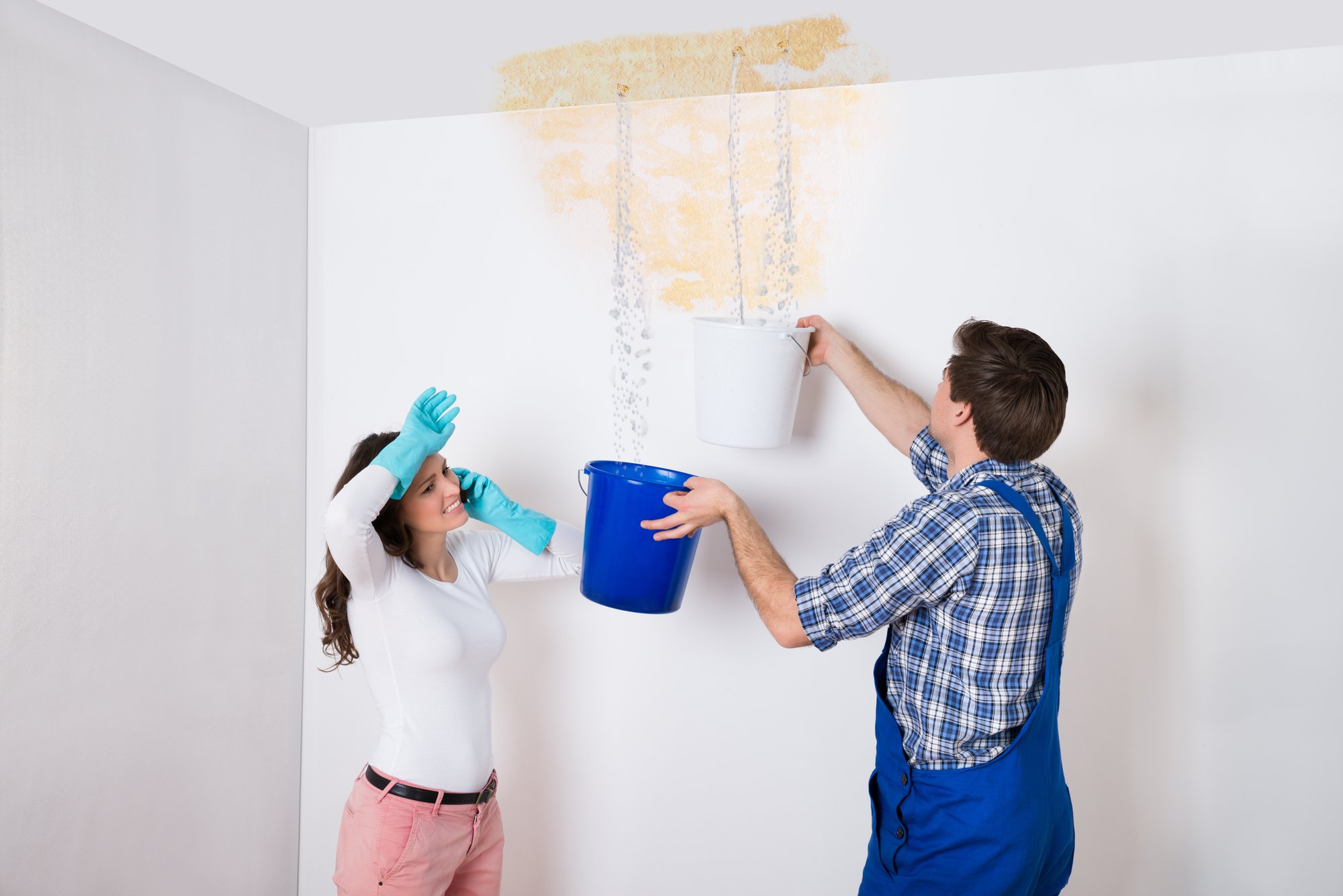 Woman With Worker Collecting Water From Ceiling In Bucket